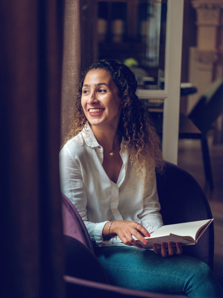 cheerful ethnic woman reading book in cafe